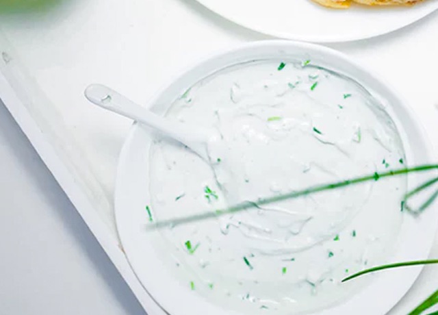 A yogurt based sauce in a bowl with a spoon