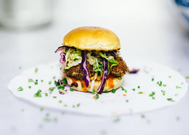 A small slider with a garnish of green onion scattered around it