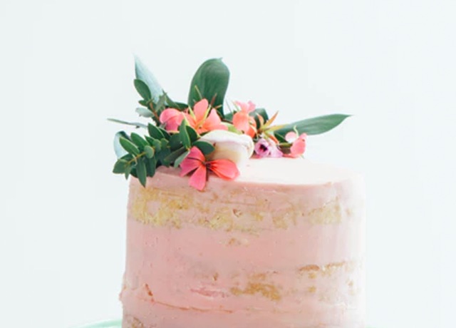 A cake with pink icing and decorative flowers on top 
